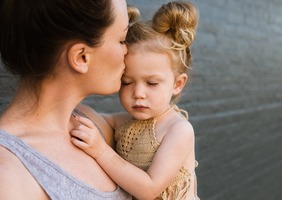 Leslie kisses the forehead of her baby girl in a touching moment.